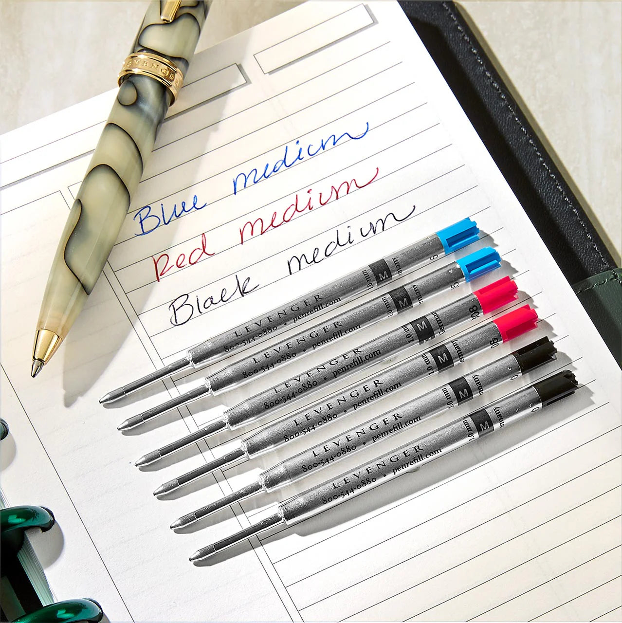 A composed flat lay of an executive folio, leather file folder, mini wallet pen, and personalized wallet cards arranged as a refined gift set.
