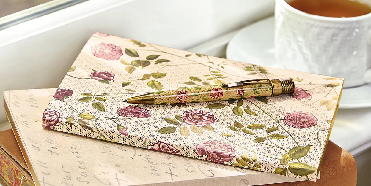 A Levenger Circa notebook open on a desk, showing labeled tab dividers, a page finder, and a pocket divider holding project materials.