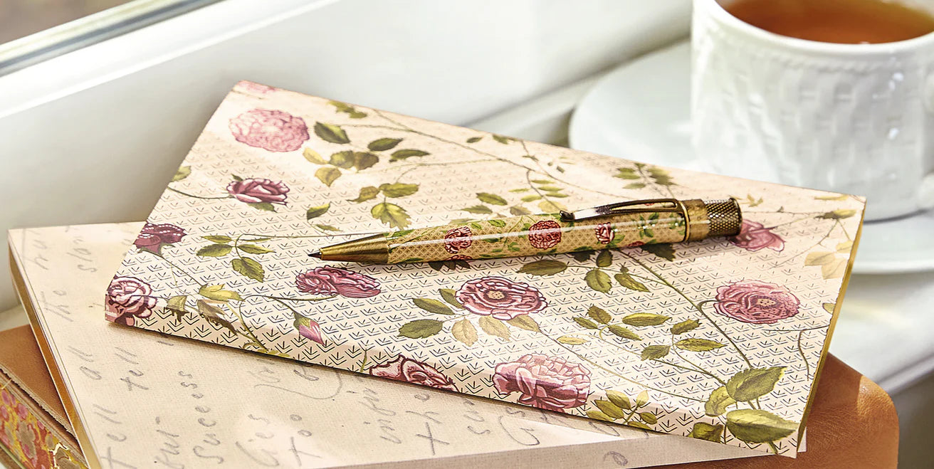 A Levenger Circa notebook open on a desk, showing labeled tab dividers, a page finder, and a pocket divider holding project materials.