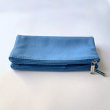 Blue canvas double zip pen case resting on a pale surface